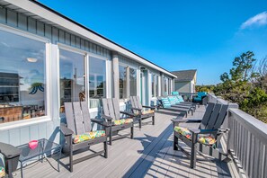 Open air deck facing ocean w/plenty of seating options & tables 