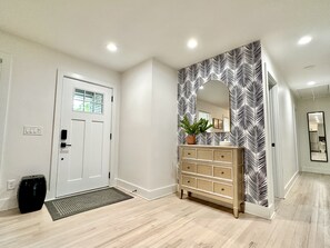 Welcoming foyer has stylish wallpaper and spot for keys and other items.