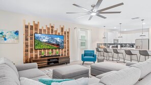 Modern open-concept living space with stylish decor, cozy seating, and a big TV!