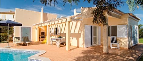 Piscine à côté de la terrasse avec chaises longues et espace barbecue