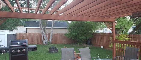 Backyard with BBQ, dining set, bear chairs, fire pit.