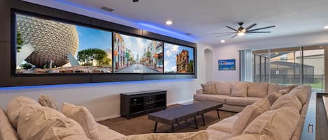 Super spacious living area with extra large sectional sofa and 3x large framed 86” TVs + pool views