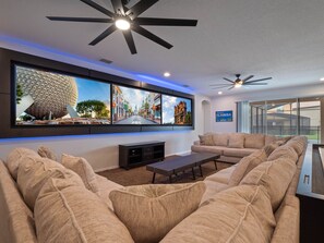 Living area with huge U-shaped sectional sofa and three large framed 86” TV