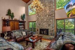 Cozy up in this luxurious mountain retreat featuring a stunning stone fireplace, vaulted ceilings, leather seating, and rustic charm. Perfect for relaxing after a day of outdoor adventure or enjoying peaceful forest views from every window.