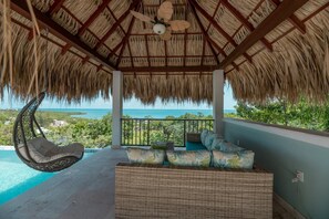 Escape the sun under the grass palapa with lights, fan and swing chair.