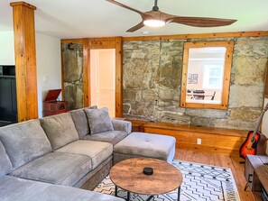 Large living room features exposed stone wall & pass through window to kitchen