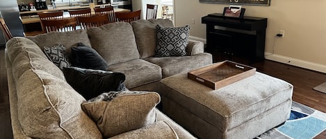 Modern living and dining area with piano, amish-made shaker style dining table, vintage marina sign, and modern kitchen with induction cooktop, vented hood, on island with bar.