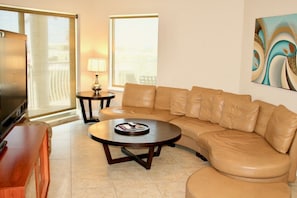 Living room with a TV, balcony access and sofa (not a sofa bed). Linens and blanke for the sofa are provided.