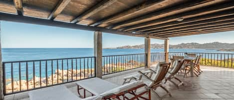 Veranda 70m² con vista a 180° sul mare, arredata con tavolo, poltrone e lettini