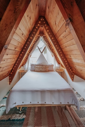 A plush sleeping loft equipped with starry lights, floor pillows, yoga stuff, sound machine, linen spray and a smart tv. Please note the windows now have a privacy film on them, its pictured in other images.