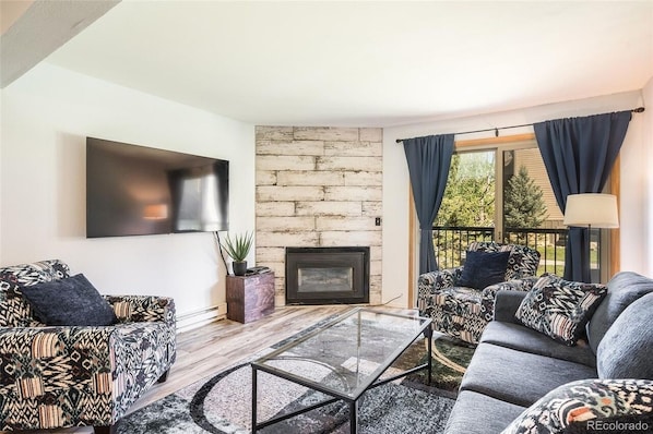 Living room with flat screen TV, fireplace and balcony overlooking common area