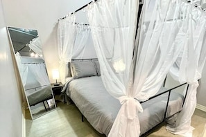 Queen-size canopy bed with sheer draped curtains.