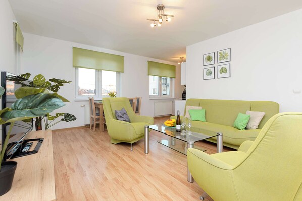 Warm and cozy living room with a sofa bed, TV, exit to balcony and dining area.