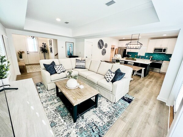 Expansive open floor layout featuring delightful coastal decor, offering convenient access to the home's rear patio.