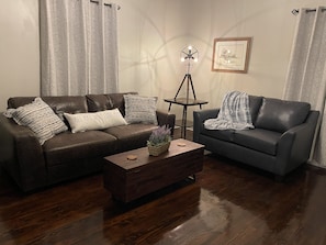 Living room features a leather couch and love seat and Alexa enabled lights