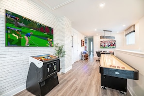 The entertainment loft offers Golden Tee Live, shuffleboard, Pac-Man, a professional poker table, and a wall-mounted Smart TV