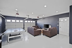 Garage game room features smart TV, ping pong table, Wii console & bar seating 