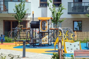 An outdoor playground with colorful equipment in front of modern residential buildings.
