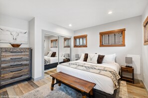 Experience ultimate comfort in the upstairs bedroom, featuring a king-size bed with a luxury mattress and linens, an electric fireplace, a 65" HD TV, and a dresser for that home-away-from-home feel