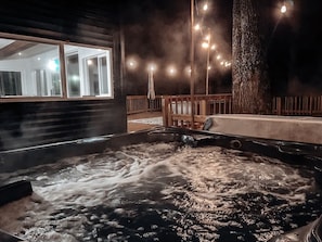 Hot tub with string lights sits just off the large deck & outdoor living space