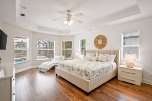 The primary bedroom has a king-sized bed and large windows that look out to the pool.