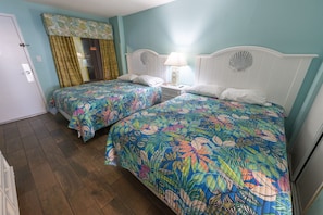 Sink into these two plush queen beds and let the soft ocean breeze lull you to sleep Vibrant tropical bedding and coastal decor create the ultimate vacation vibe Whether you're unwinding after a beach day or sleeping in, this room is pure comfort