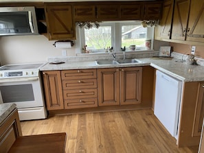 Kitchen with microwave above stove, dishwasher, frig, coffee maker and toaster