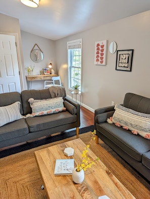 Living room with 2 couches and smart tv. Cabinet with games and puzzles.