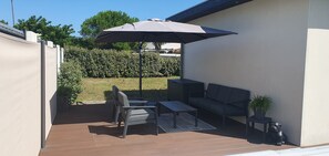 Salon de jardin abrité par un grand parasol inclinable