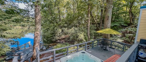 View from the back deck overlooking the hot tub, patio set, and fire pit. 