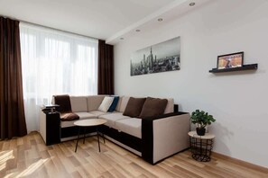 Another view of the living room, showcasing the same sectional sofa and coffee table. A large window provides natural light, adding to the bright and inviting ambiance.