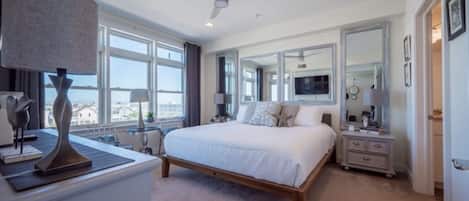 The master suite offers designer decor, king bed, and stunning bay views.