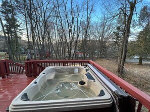 Hot tub on the front porch with lake views through the trees