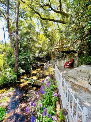 Unwind on the dreamy backyard terrace overlooking a wooded babbling creek.