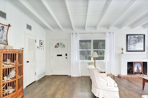 Front Entry – Light-Filled Living Room at Mocama - Step in from the Jekyll Island breeze to painted beams, soft light, and original mid-century detail—Mocama’s charm kicks in before you’re even fully inside.