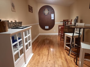 Lounge with bar tables, dart board and a variety of bar glassware.