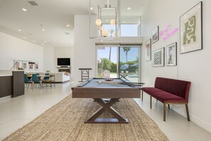 Pool table surrounded by natural light indoors.