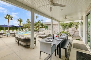 Poolside patio features an outdoor living area and a covered dining table. 