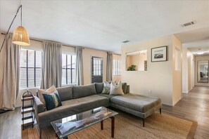 Large living room with modern sofa open to dining area.