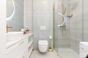 Modern bathroom with a walk-in shower, sleek white fixtures, and light tiles.
