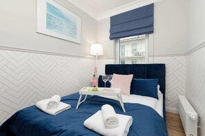 Cozy bedroom featuring a plush navy blue bed, bedside table, and stylish artwork.
