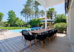 Terrasse coté salon donnant sur la piscine, la cuisine extérieure et le jardin.