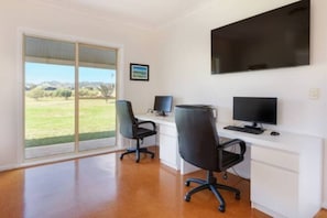 An executive office features two desks with monitors, under a flat-screen TV, with views across the valley.