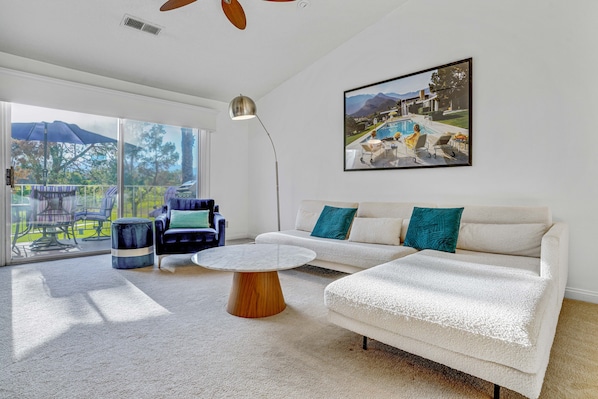 Living room with private balcony and view of golf course and mountains.