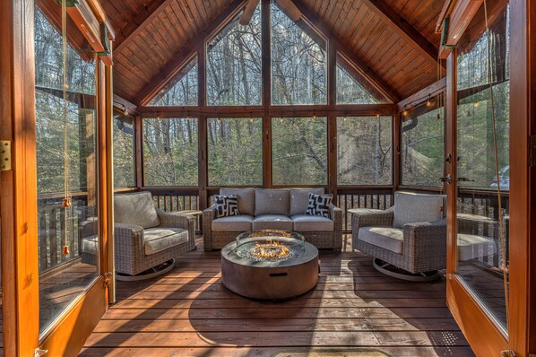 Upper level screened porch with conversation seating and gas fire pit. 