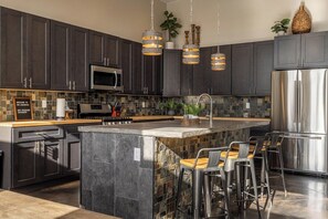 Where exposed tiles and dark sophisticated cabinetry set a cozy tone, the kitchen makes the perfect place to gather, create, and share delicious meals during your stay.