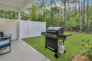 Peaceful backyard with patio seating and gas grill