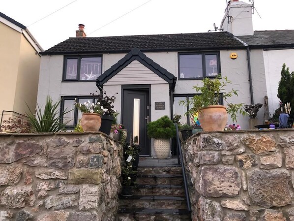 Steps leading to elevated position of double fronted cottage. Walled garden.