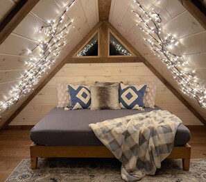 Our charming cabin loft is the perfect place to cozy up with a good book tucked beneath a set of romantic string lights that cast a warm, inviting glow. This loft is the ideal spot for quiet nights spent with your favorite person!