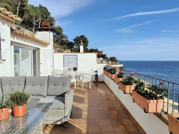 The spacious terrace of this penthouse apartment boasts stunning sea views and offers a tranquil escape. Relax on the comfortable sofa while enjoying the fresh air and sunshine, or dine al fresco at the table surrounded by the lush greenery.
